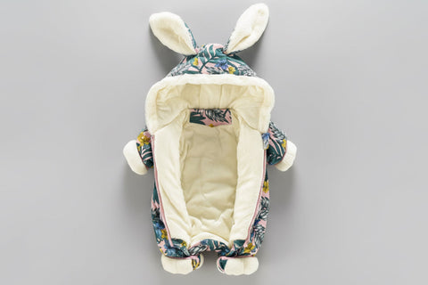Floral-patterned baby bouncer with bunny ears on a gray background