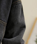 Close-up of a dark denim jacket with a brand label, blurred background