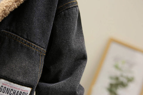 Close-up of a dark denim jacket with a brand label, blurred background