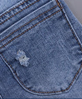 Close-up of a blue denim pocket with a small tear on a gray background