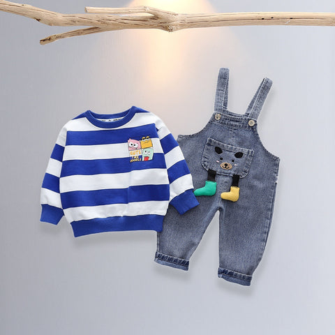 Children's blue and white striped sweater with cartoon design and denim overalls on a light gray background.