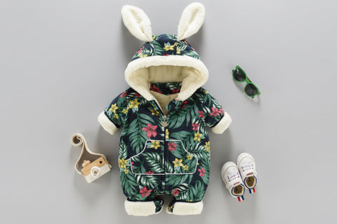 Children's floral onesie with bunny ears, baby shoes, and a small bag on a gray background