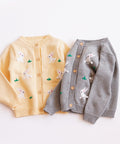 Two children's cardigans, one yellow and one gray, with cartoon designs on a white background.