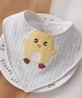 Gray baby bib with a chick design on a white surface