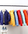Colorful puffer jackets on a rack with a white background