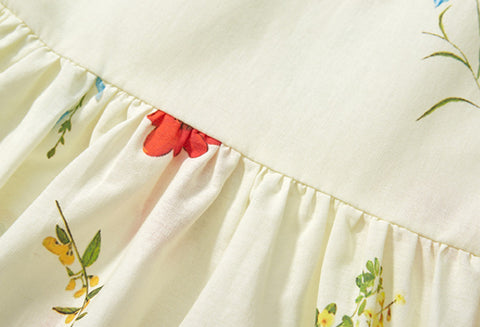 Close-up of a white dress with floral embroidery and red accents.