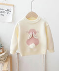 Children's sweater with bunny design on a hanger against a white wall.