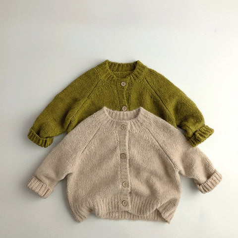 Two knitted cardigans, one green and one beige, on a light gray background.