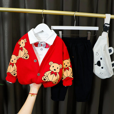 Red cardigan with bear pattern on a hanger against a black curtain background