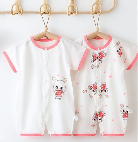 Baby rompers with cartoon designs on hangers against a white wall.