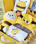 Baby outfit set with bee-themed items including a plush toy, hoodie, and bib in a yellow suitcase.