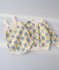 Knitted baby romper with floral pattern on a white surface