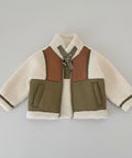 Shearling jacket with brown and green accents on a wooden surface
