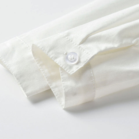 Close-up of a white shirt with a button on a light gray background