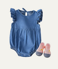 Blue baby romper with ruffled sleeves and pink baby shoes on a light gray background